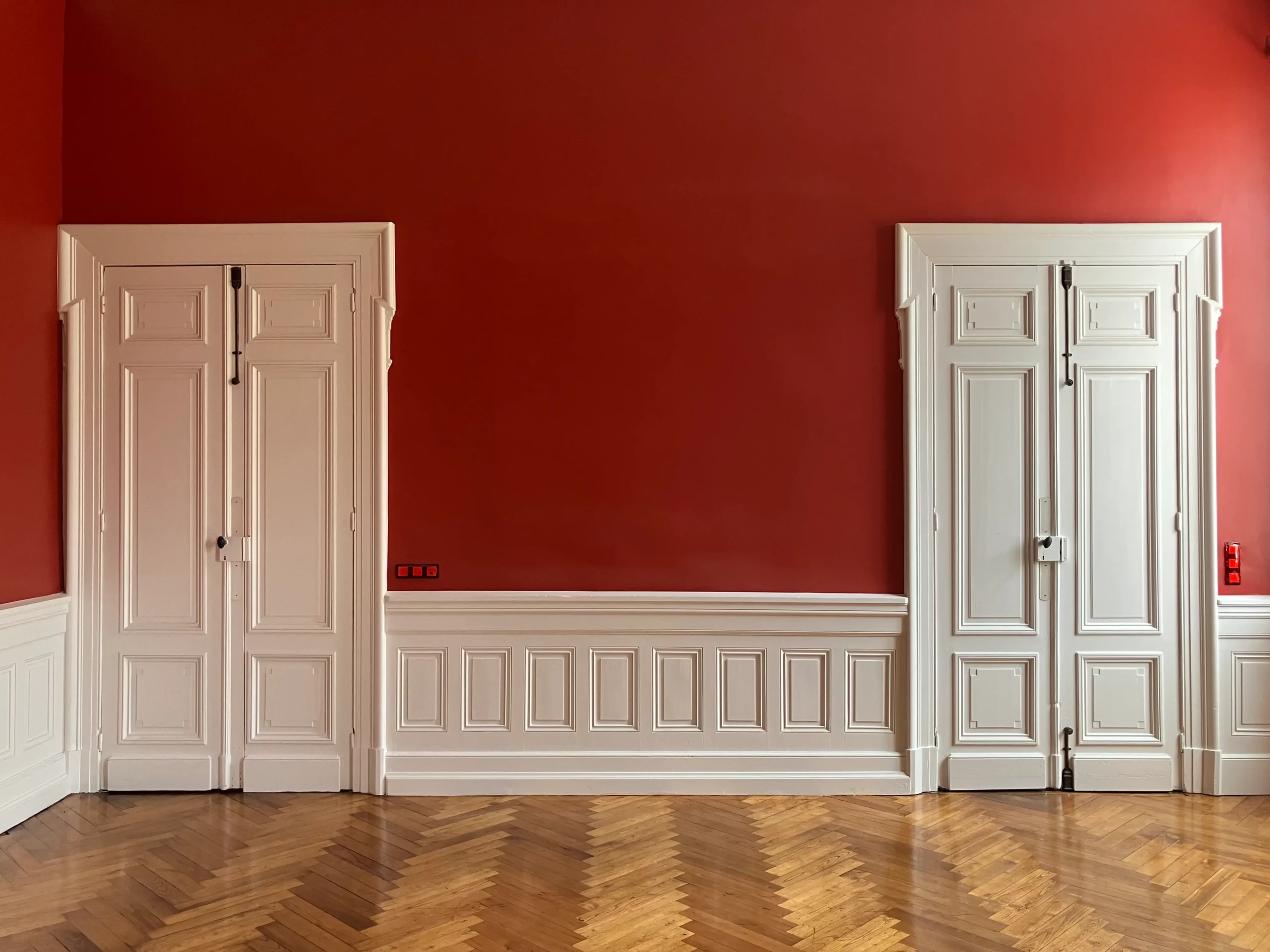 Vue générale du grand salon restauré avec deux grandes portes et parquet.